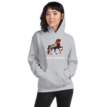 Load image into Gallery viewer, A woman modeling an &quot;I Want To Believe&quot; Unisex Hoodie from Real Unicorn Apparel. The hoodie is grey and features a rainbow-colored unicorn for LGBT pride. 

