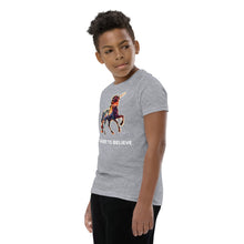 Load image into Gallery viewer, A side profile photo of a middle school African-American boy wearing an &quot;I Want To Believe&quot; (In Unicorns) t-shirt from Real Unicorn Apparel. The tee has a unicorn designed by Lauren Rubin. 
