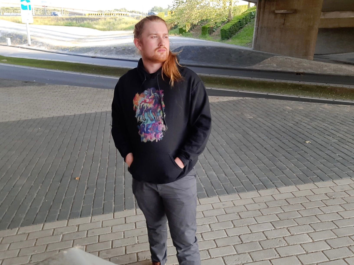 A photo of a Dutch male model with long red hair wearing a Real Unicorn Apparel hoodie that features unicorn symbolism