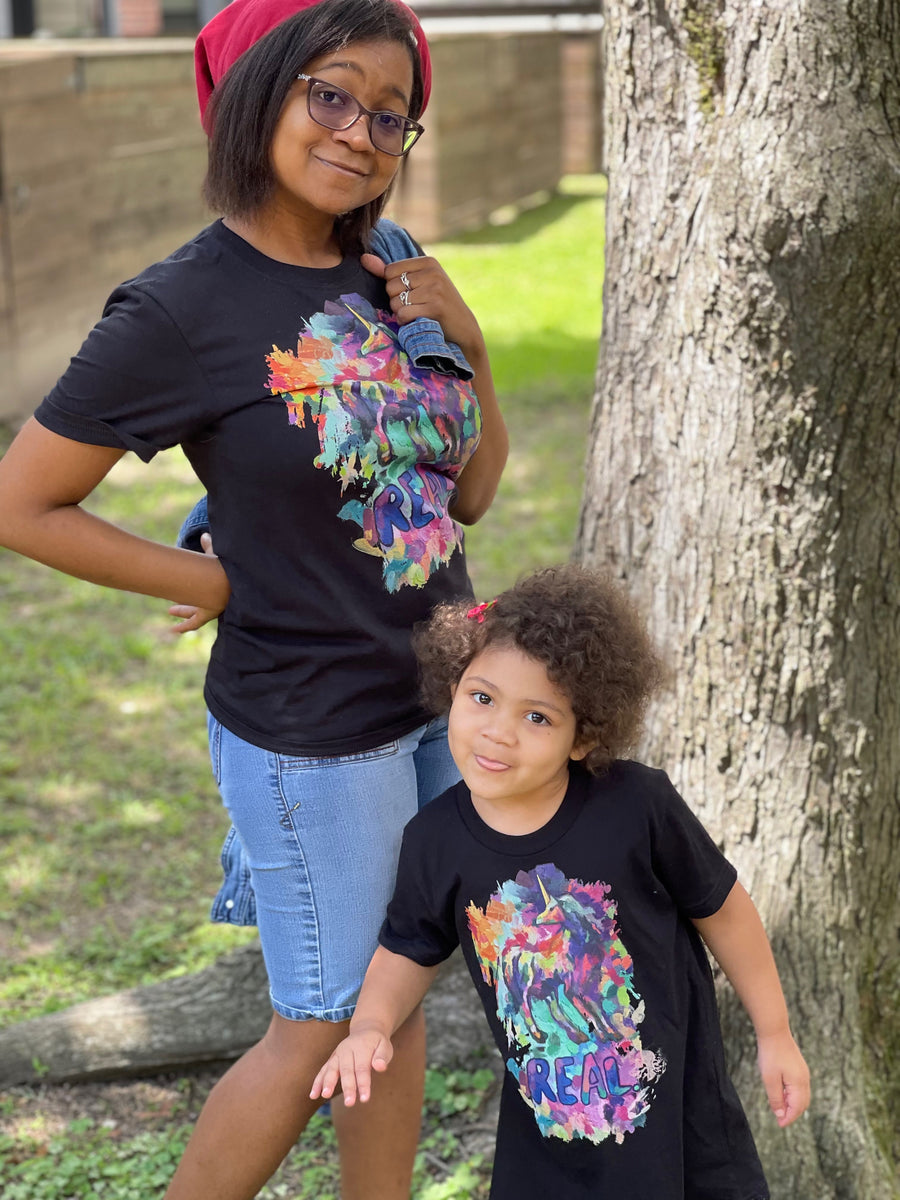 A photo of a mother and daughter wearing matching Real Unicorn Apparel t-shirts infused with unicorn symbolism