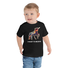 Load image into Gallery viewer, A blond toddler wearing a black &quot;I Want To Believe&quot; short sleeve t-shirt from Real Unicorn Apparel. 
