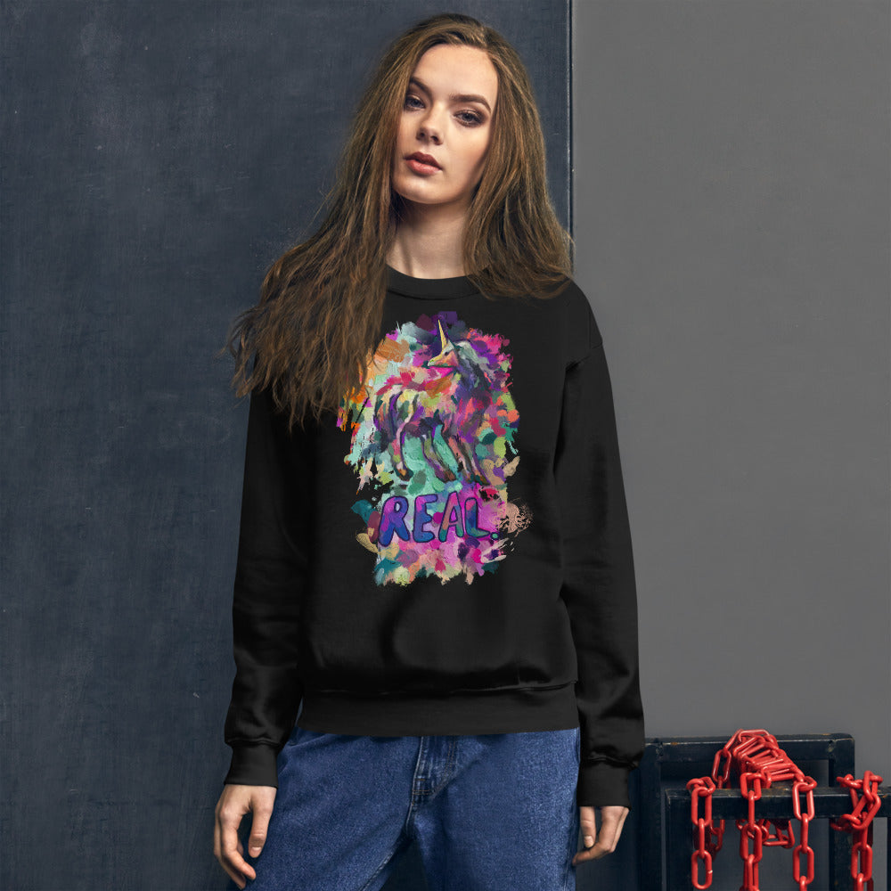 A model wearing a black Real Unicorn Unisex Sweatshirt from Real Unicorn Apparel. The sweatshirt has a graphic of a unicorn with the word 