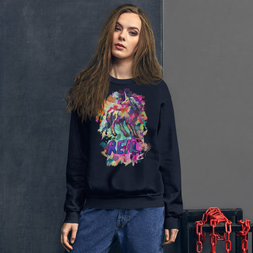 An attractive woman wearing a navy-colored Real Unicorn Unisex Sweatshirt from Real Unicorn Apparel and a pair of blue jeans. Some orange chains are to the side of her right hip.
